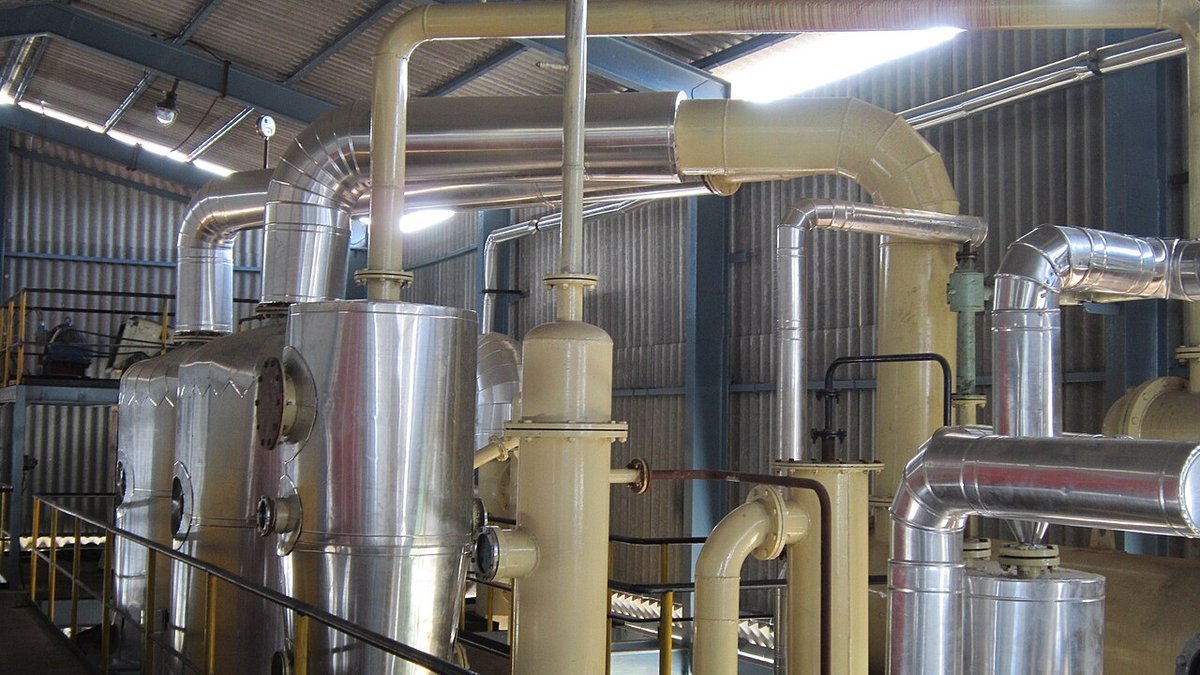 Industrial chemical solvent extraction plant showing distillation fractionation column and solvent recovery piping