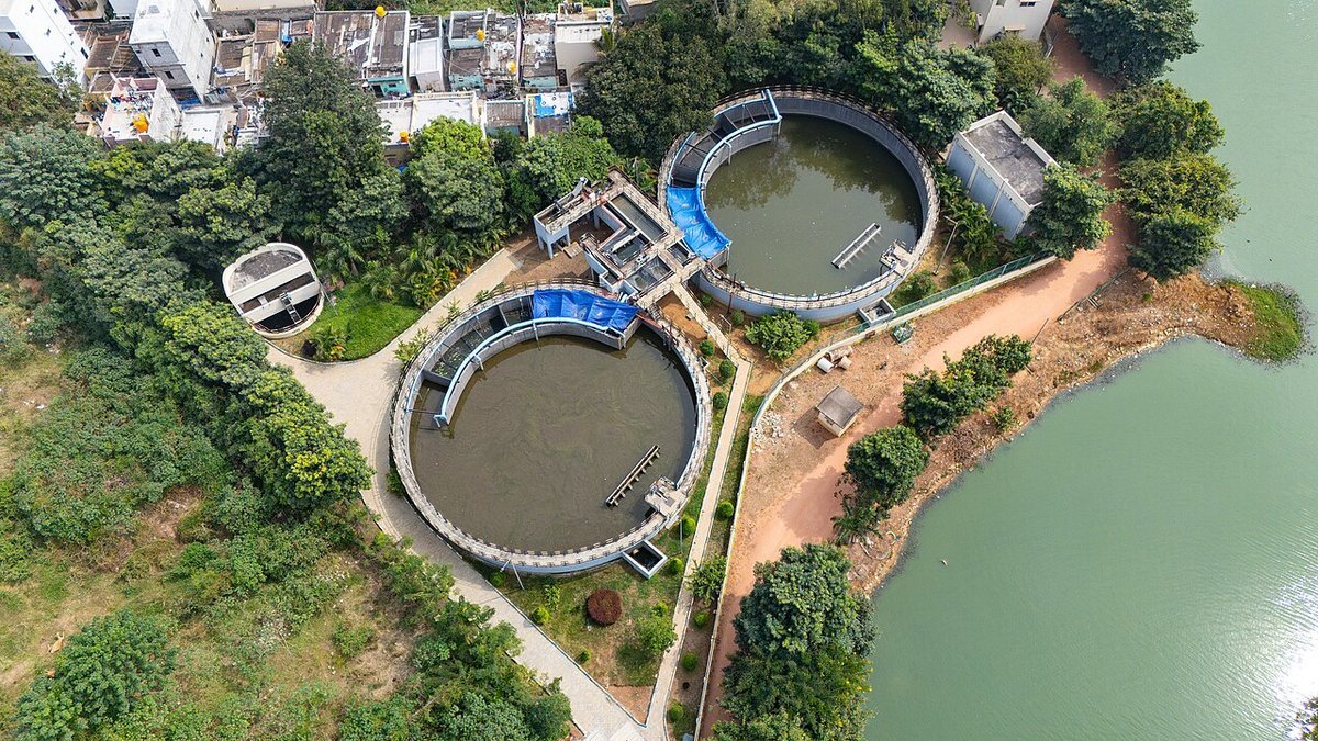 Aerial view of circular biological wastewater clarifier basins with rotating bridge scraper and effluent discharge weir