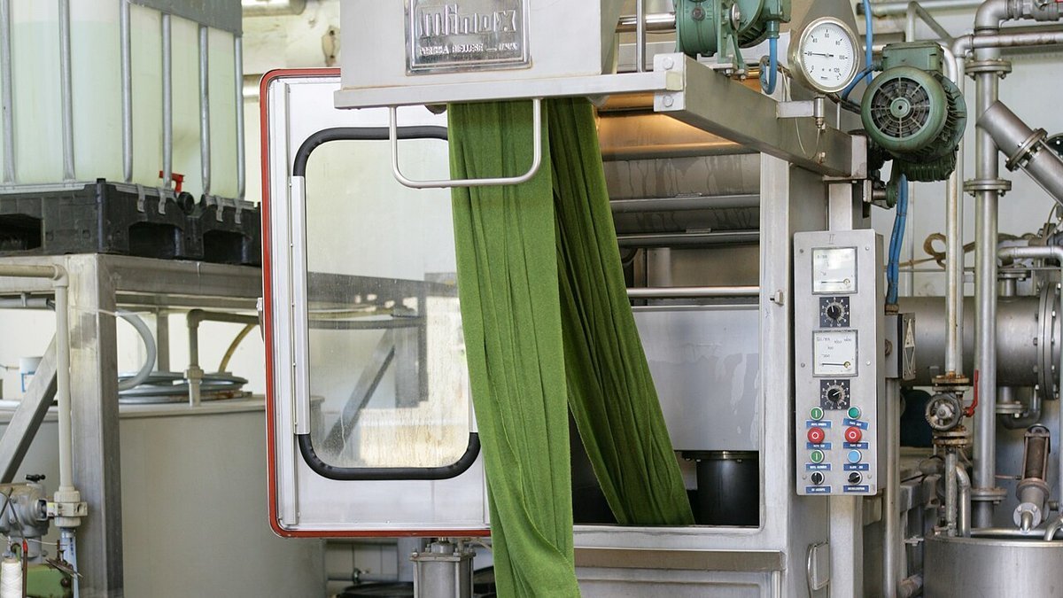 Continuous textile fabric dyeing machine with chemical IBC tote supply and dyed knit fabric tub